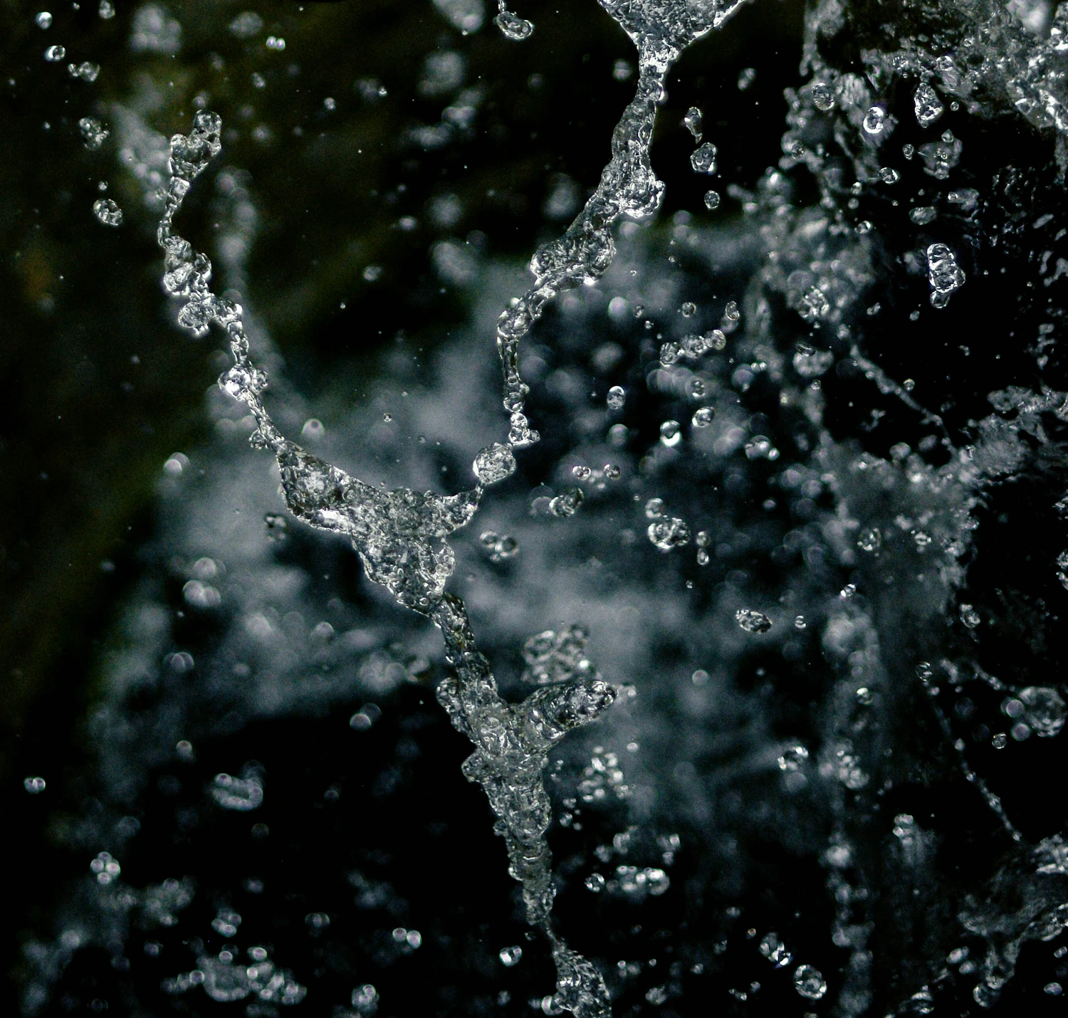 A column of water tearing apart in mid-air against a near-black background