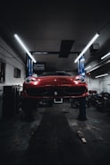 A technician performing an oil change on a sleek vehicle under bright workshop lights.