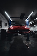 A technician performing an oil change on a sleek vehicle under bright workshop lights.