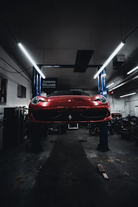 A close-up of a car battery being installed in a sleek black vehicle under bright workshop lighting.