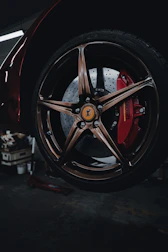 A skilled technician inspecting a Ferrari brake caliper in a well-lit workshop.