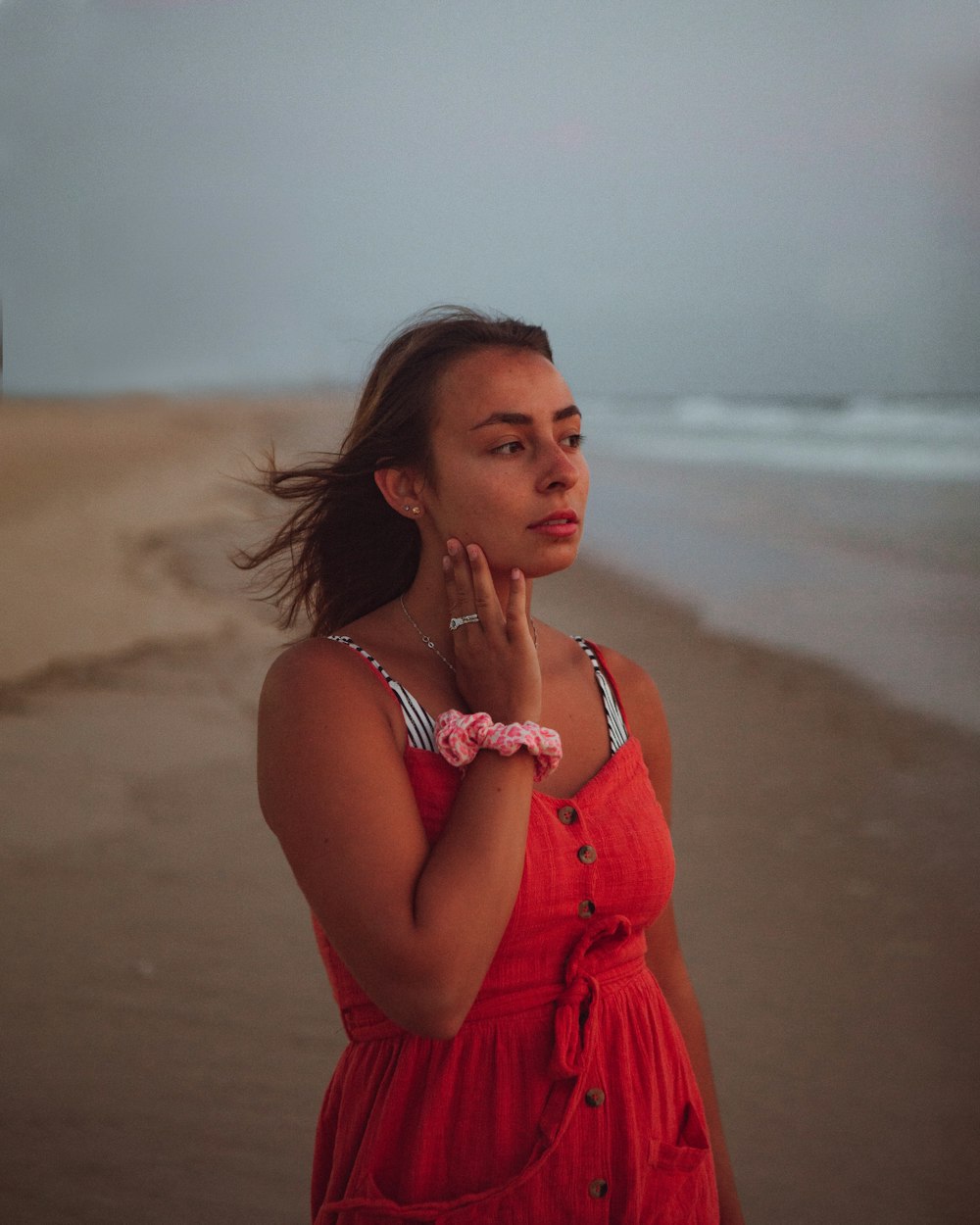 mulher no vestido vermelho da alça do espaguete que está na praia durante o dia