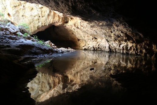 A serene cave interior with a single beam of light illuminating a wooden altar.
