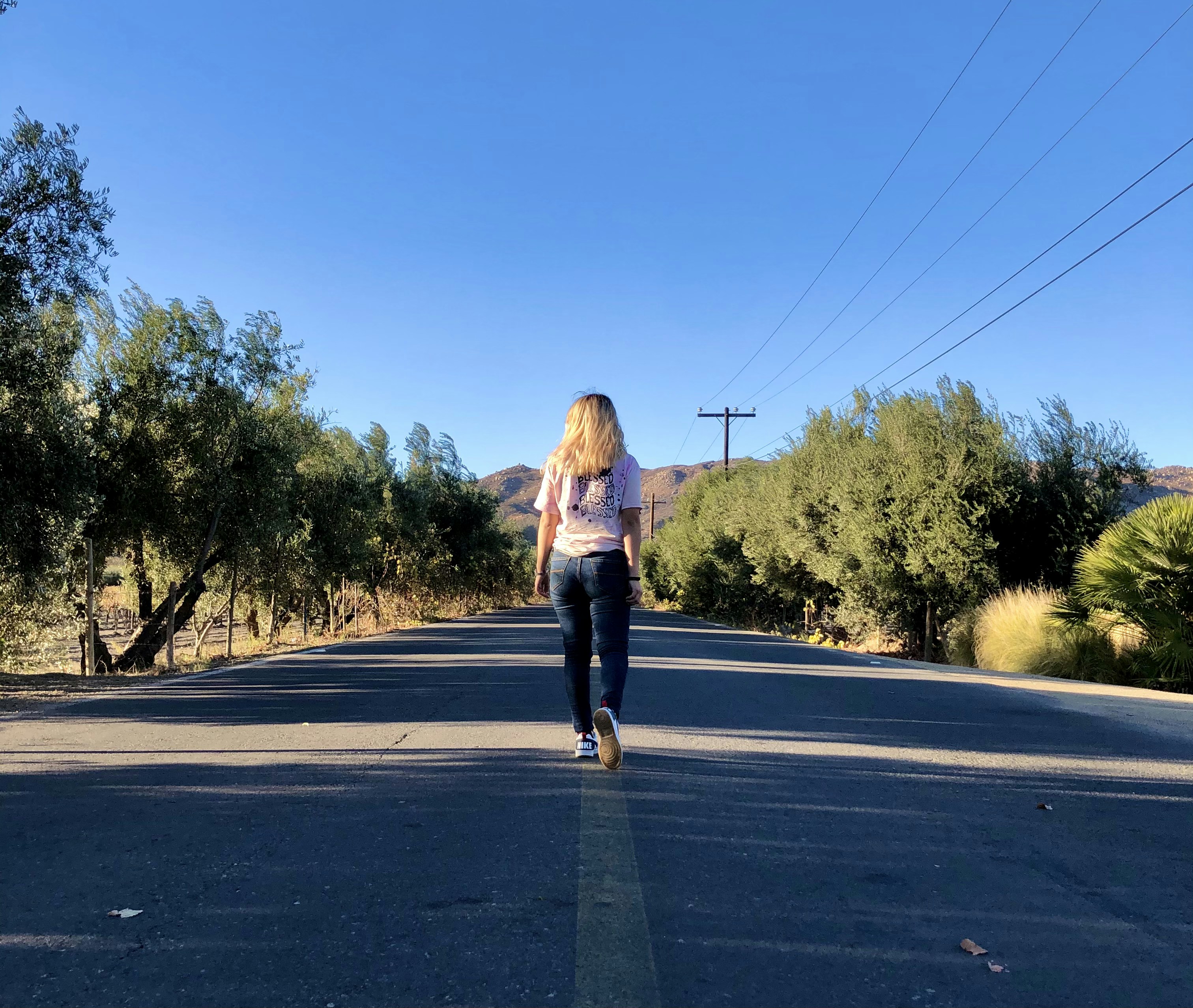 woman in gray long sleeve shirt and black pants standing on gray asphalt road during daytime