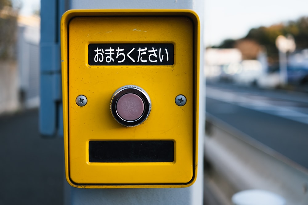a close up of a yellow button on a pole