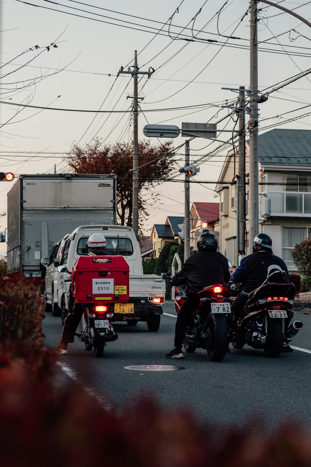 man in black jacket riding motorcycle near red car during daytime