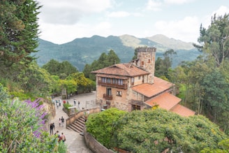 brown concrete houses near green trees and mountain during daytime