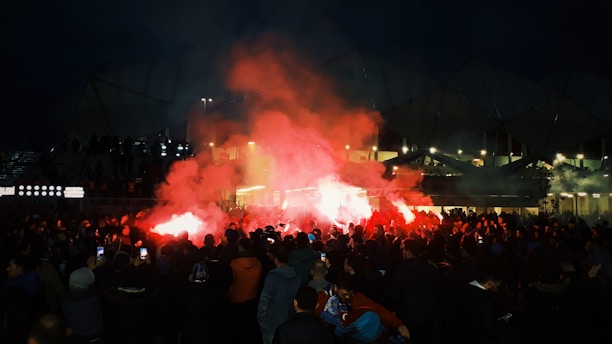 A vibrant crowd of Flamengo fans celebrating a goal at Maracanã Stadium during a night match.