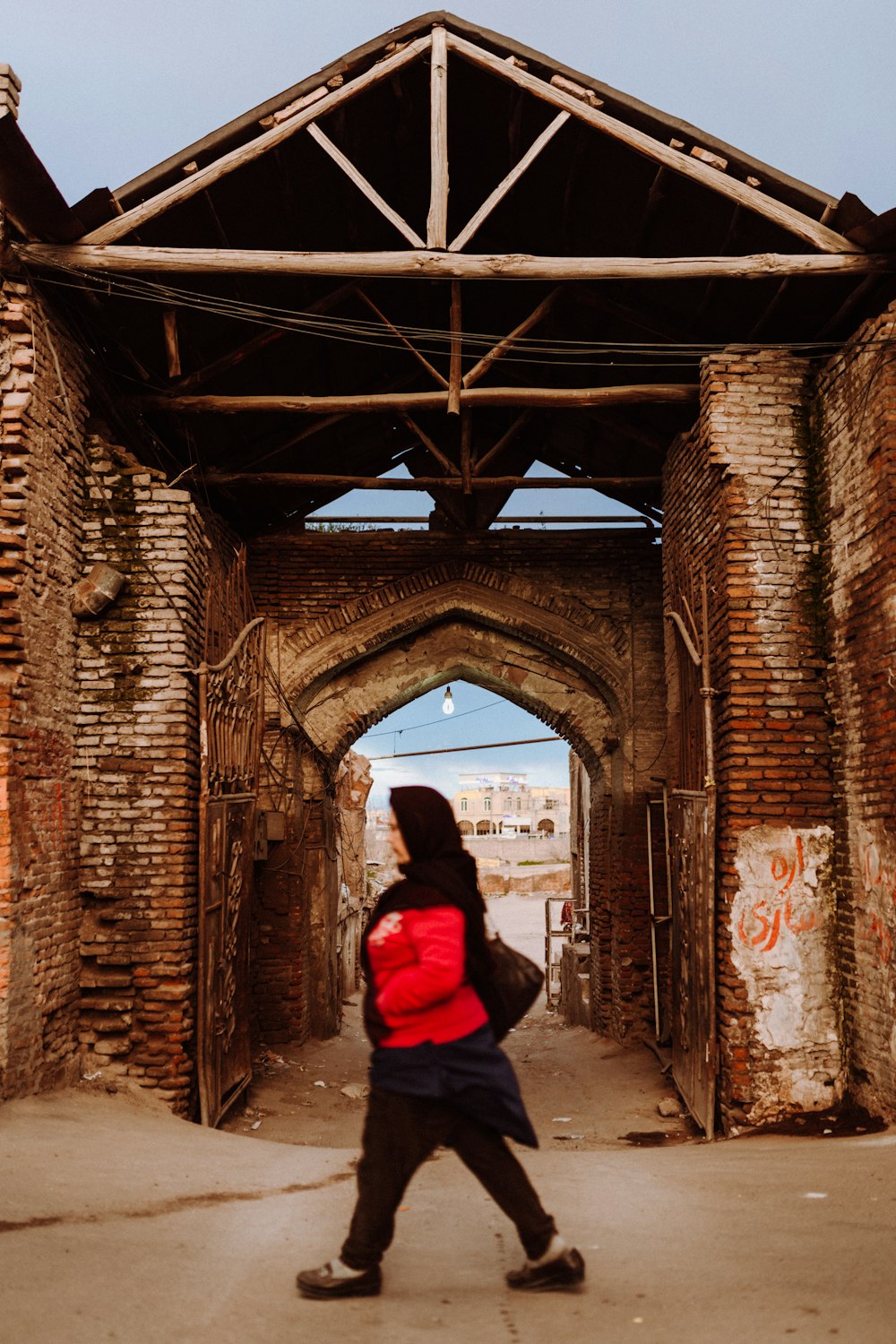 person in red hoodie standing in front of brown brick wall