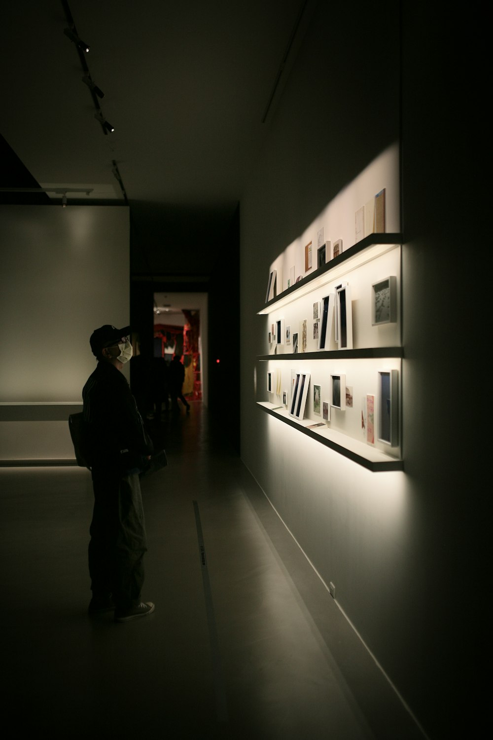 man in black jacket standing near white wall