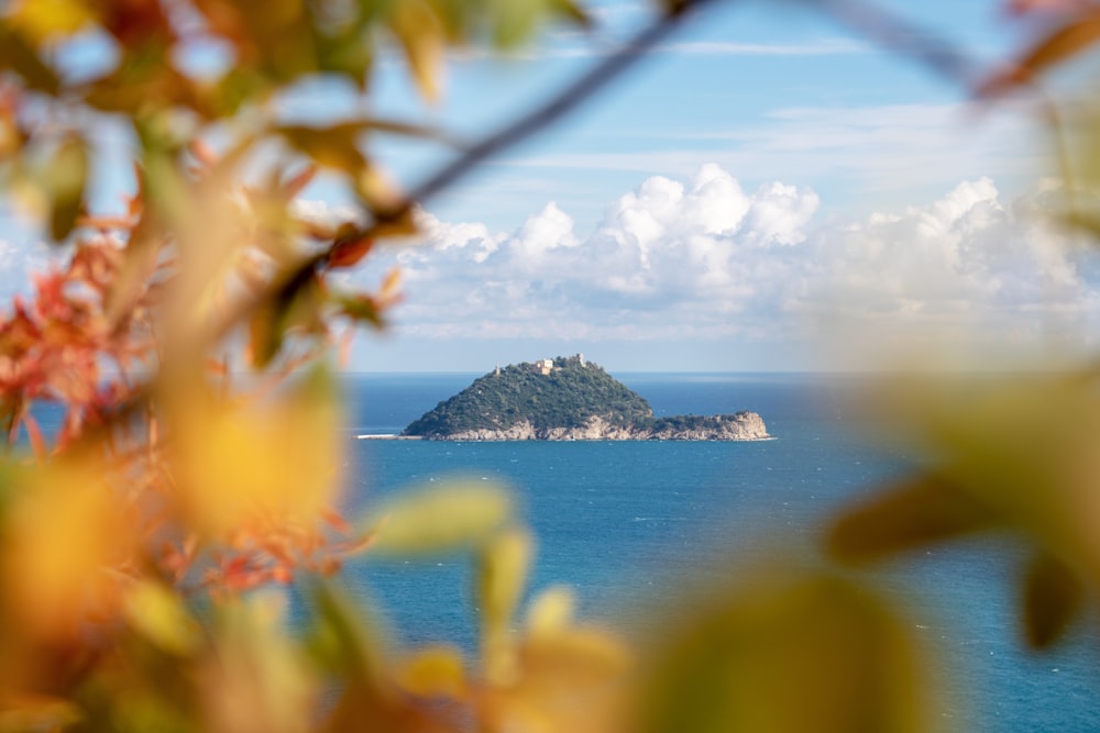 green island on body of water under blue sky and white clouds during daytime