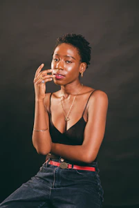 A softly lit photo of a stylish woman in a rose-gold accented bra and jeans, exuding calm confidence.