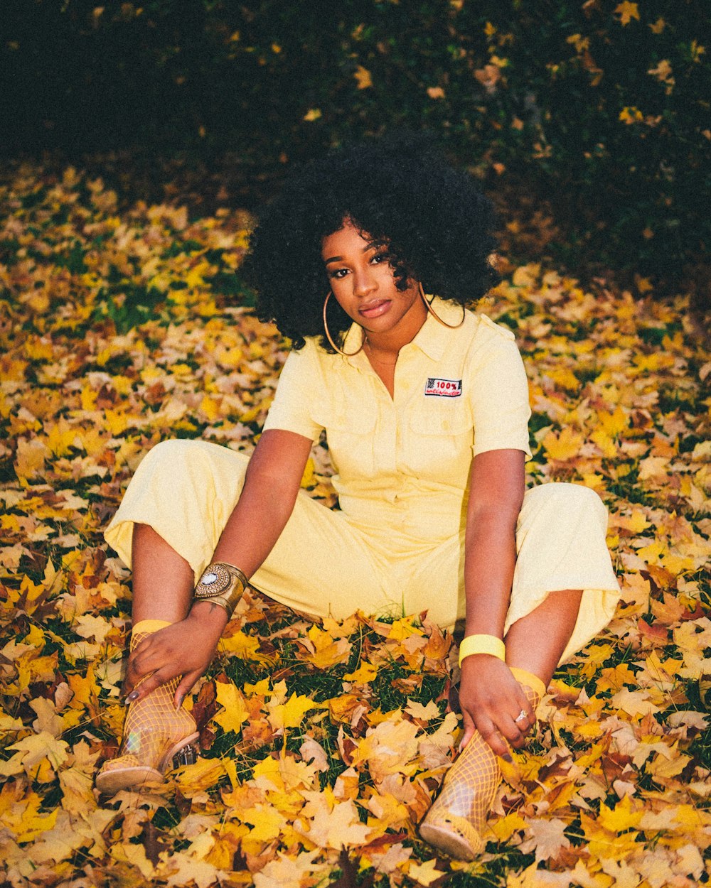 woman in white crew neck t-shirt and yellow shorts sitting on yellow leaves
