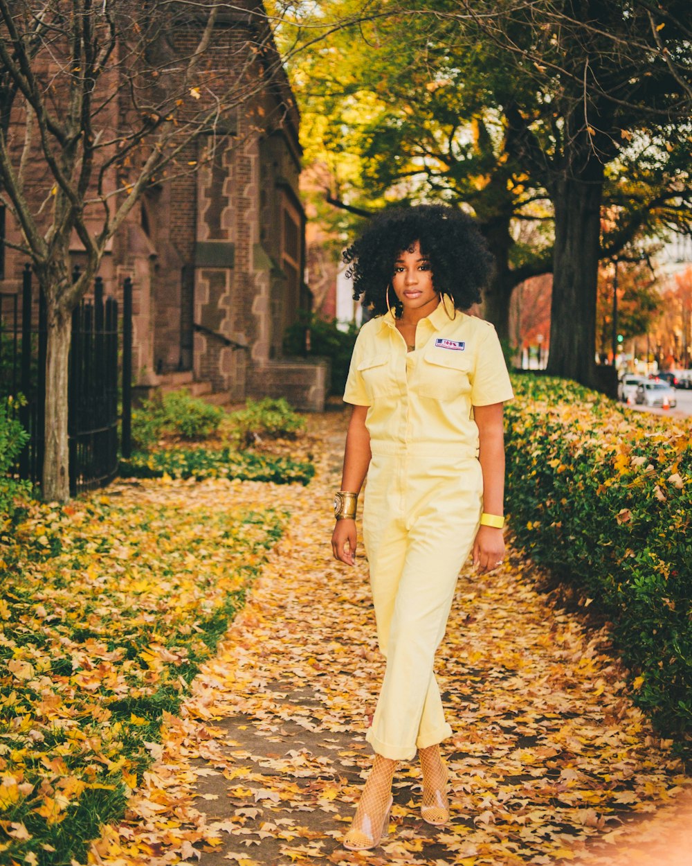 woman in white polo shirt and beige pants standing on brown leaves on ground