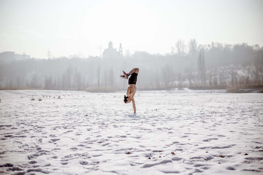 woman in black tank top and brown shorts jumping on snow covered ground during daytime