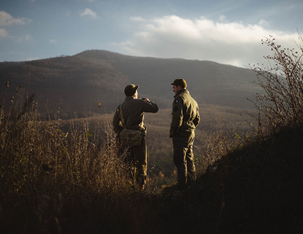 2 men standing on brown grass field during daytime