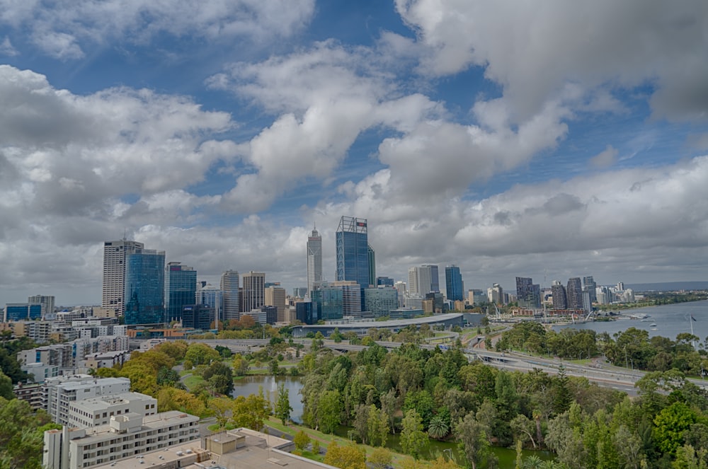green trees and city buildings under white clouds and blue sky during daytime