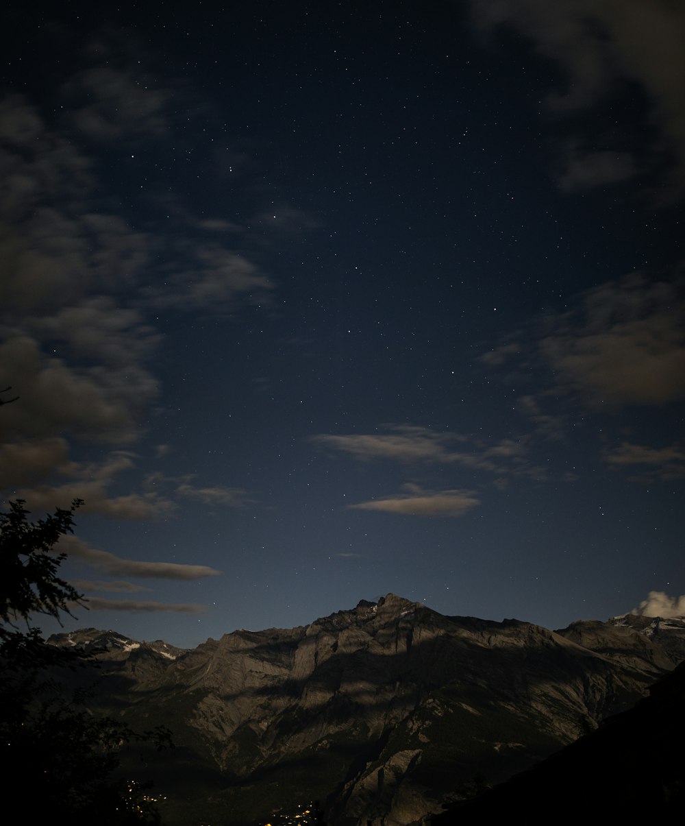 silhouette of trees and mountains under blue sky and white clouds during daytime