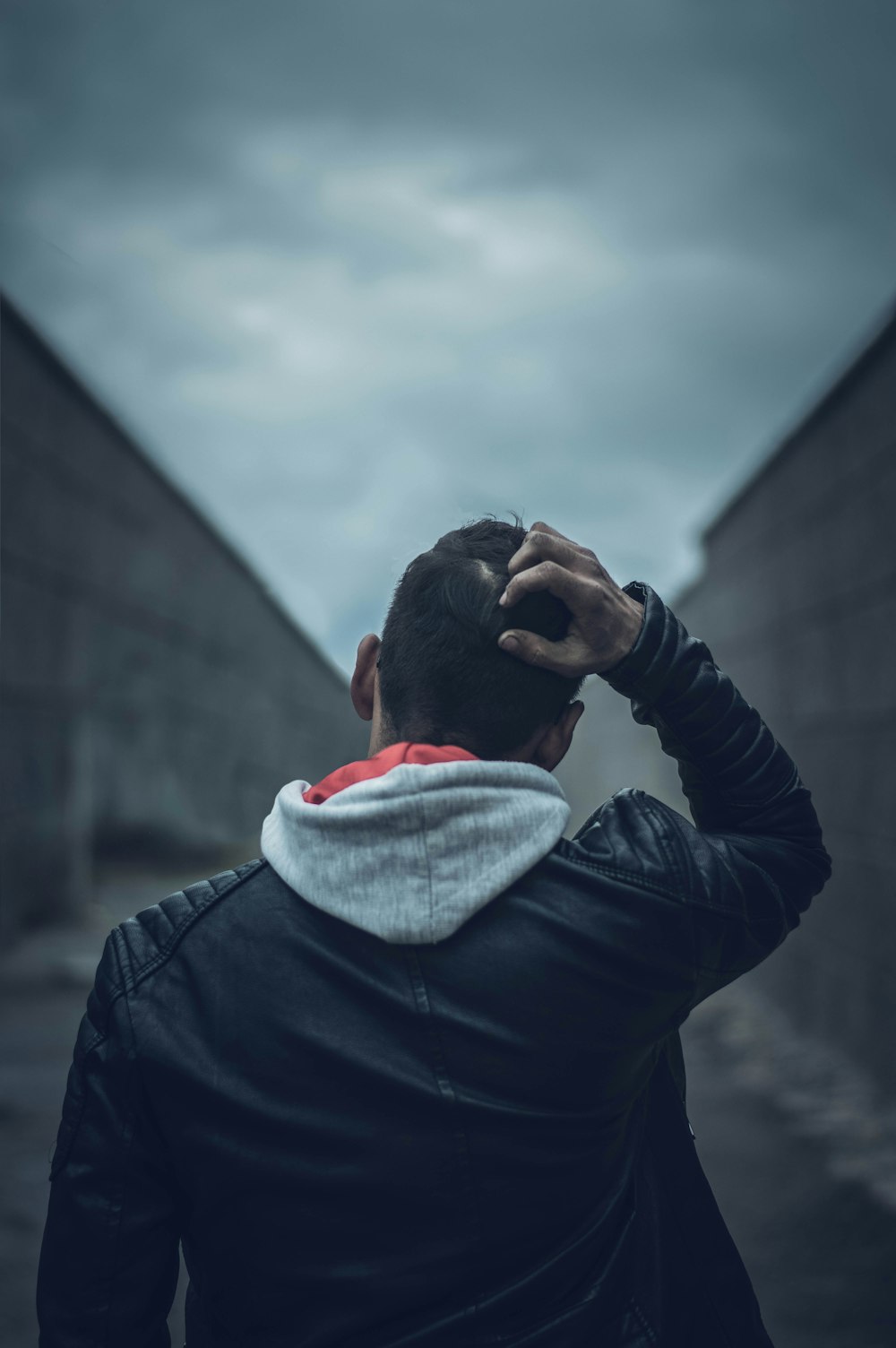 Hombre con chaqueta de cuero negro que cubre su rostro con bufanda blanca y roja