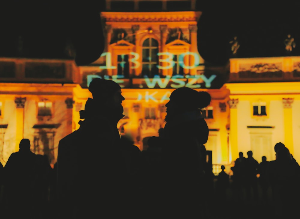 silhouette of people standing near building during night time