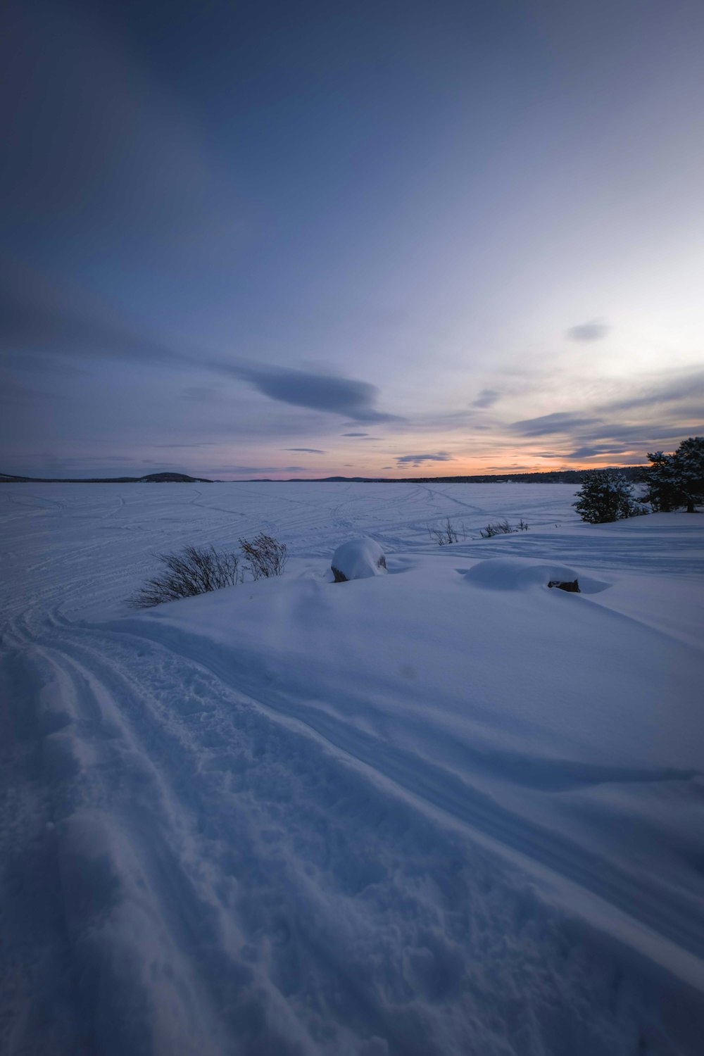 snow covered field under cloudy sky during daytime