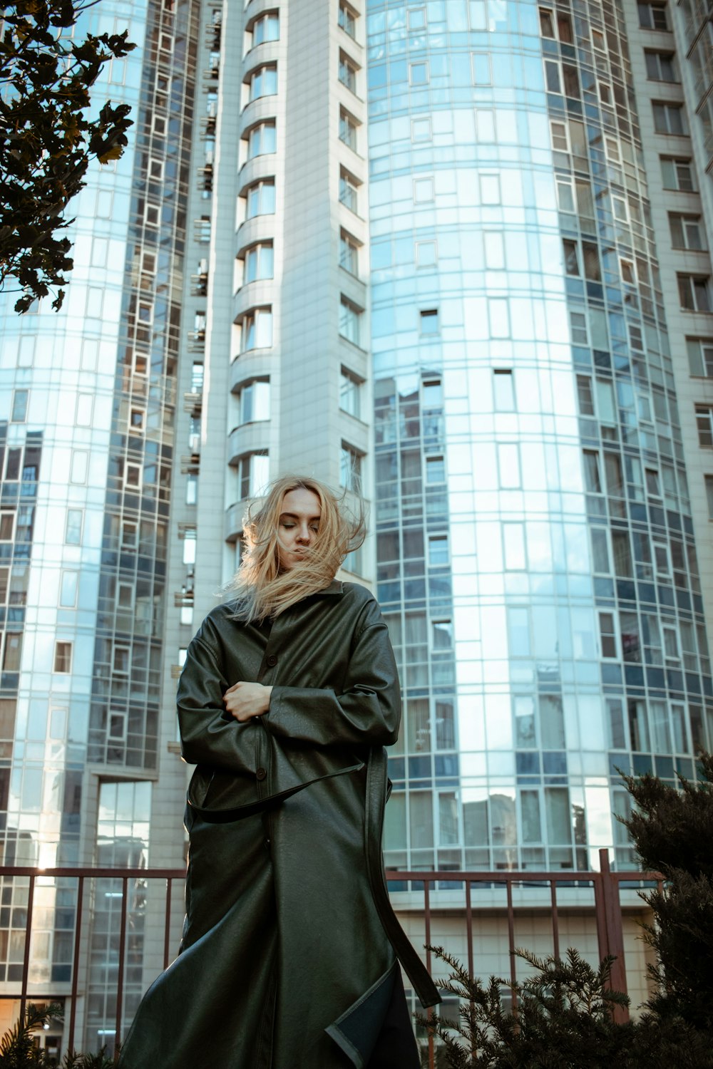 woman in black coat standing near white high rise building during daytime