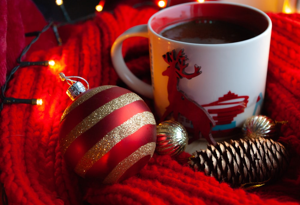 white ceramic mug with coffee beside red and white striped baubles