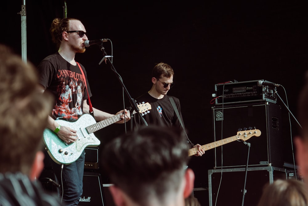 man in red and white floral shirt playing electric guitar