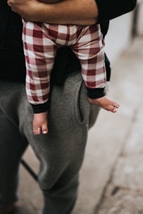 person in red white and black plaid long sleeve shirt and gray pants sitting on black