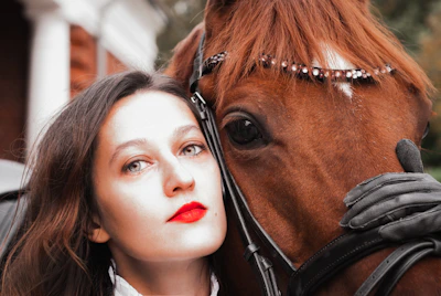 woman in black leather jacket beside brown horse