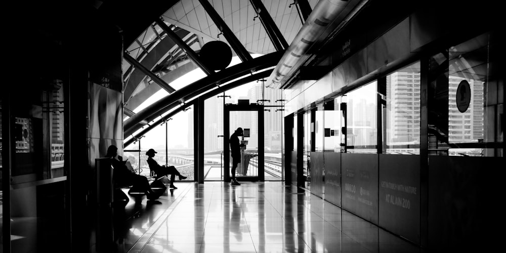 grayscale photo of people sitting on bench inside building