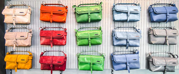 Close-up of stylish handbags and backpacks in various textures and colors on a shelf.