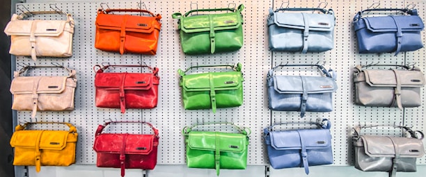 A vibrant display of colorful handbags and accessories arranged on a stylish wooden table.