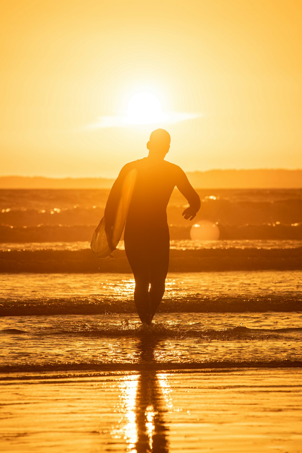 silhouette of man holding surfboard on beach during sunset