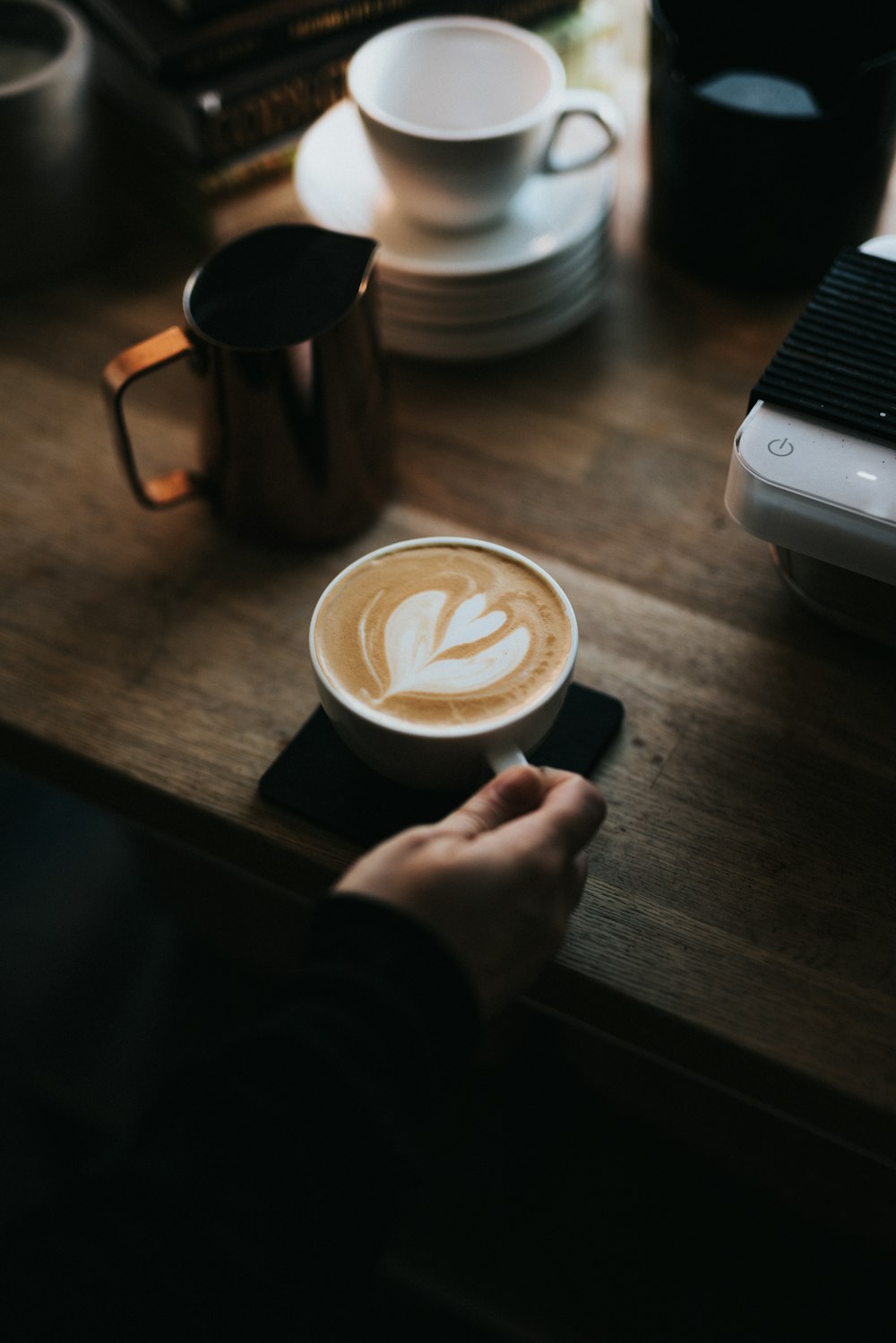 person holding white ceramic mug with cappuccino