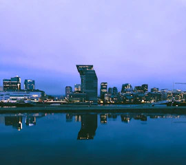 Artistic photo of a cityscape at dusk with soft natural light and reflective surfaces.