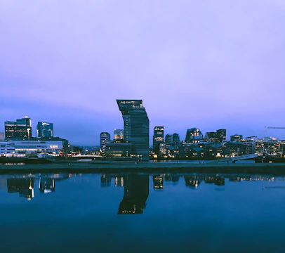 Artistic photo of a cityscape at dusk with soft natural light and reflective surfaces.