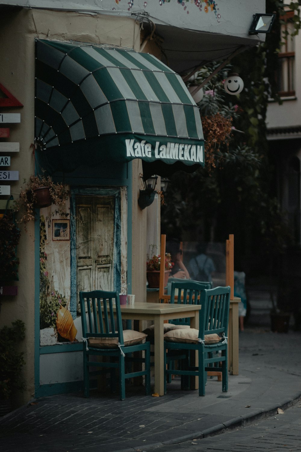 Sillas y mesa de madera marrón cerca de la tienda verde y blanca