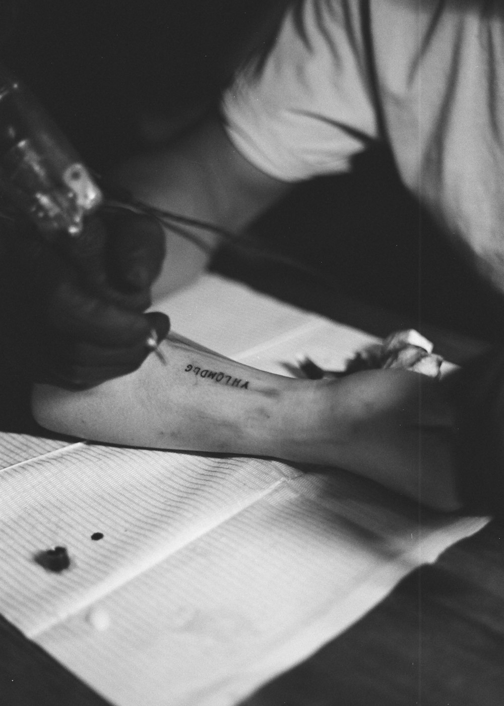 pessoa segurando uma caneta e um papel com uma tatuagem