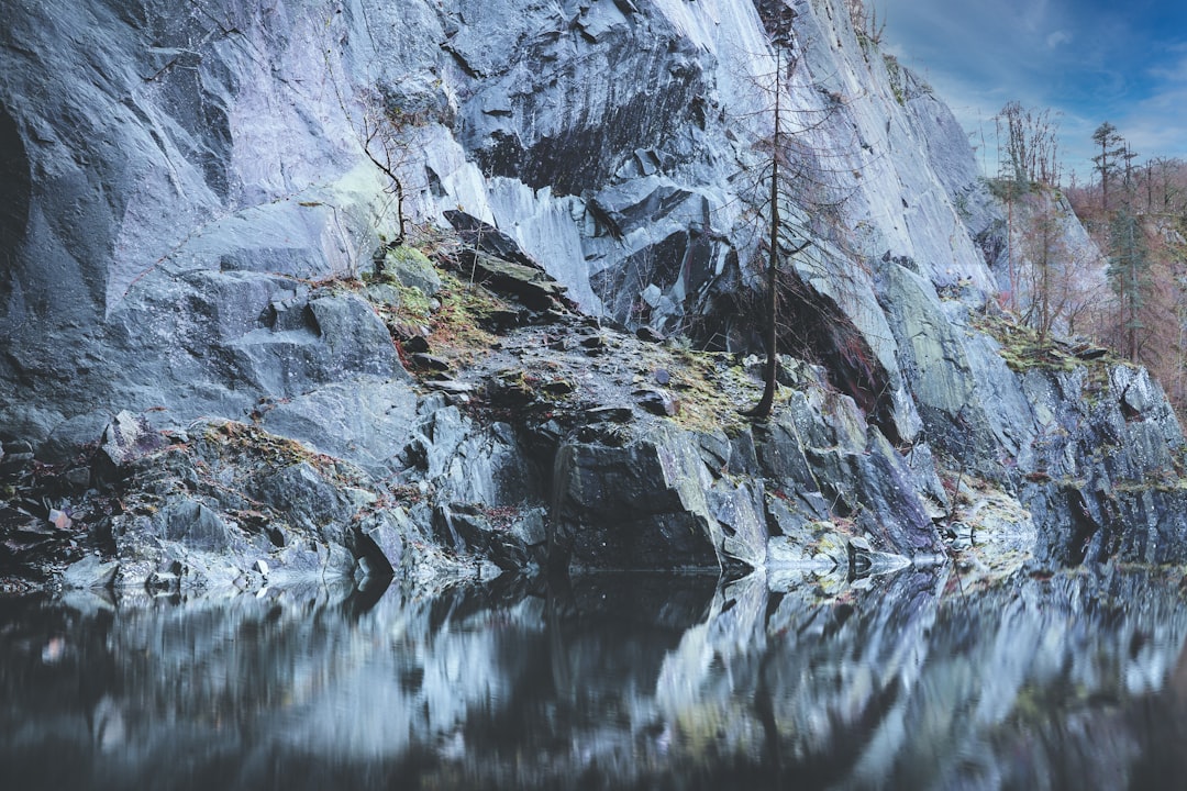 gray rocky mountain beside body of water during daytime