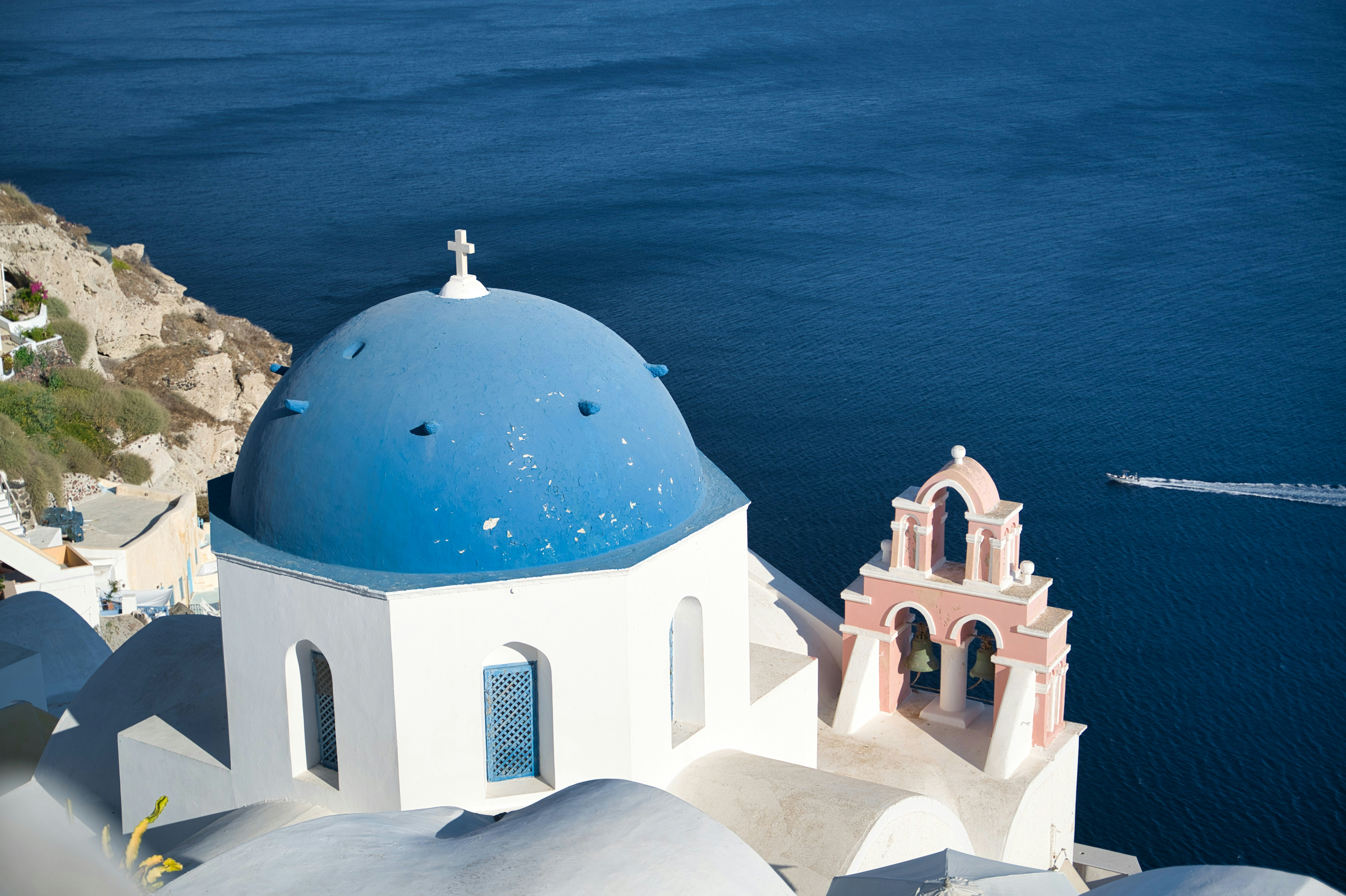 blue dome building near body of water during daytime, Sunset view Oia village on Santorini Greece