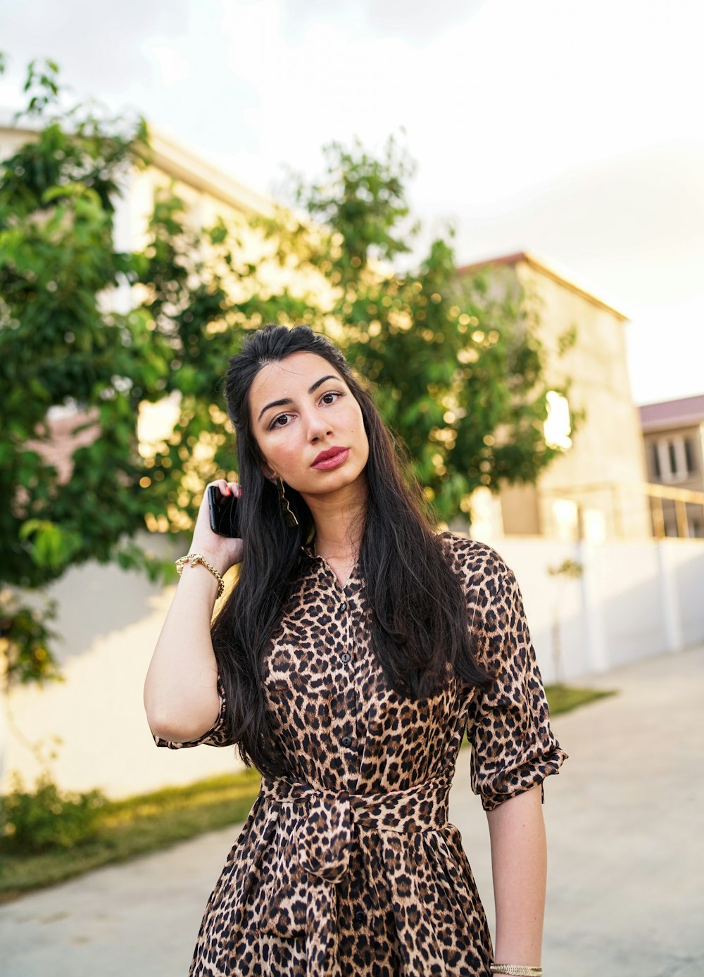 Mujer en vestido blanco y negro con estampado de leopardo sosteniendo un teléfono inteligente negro