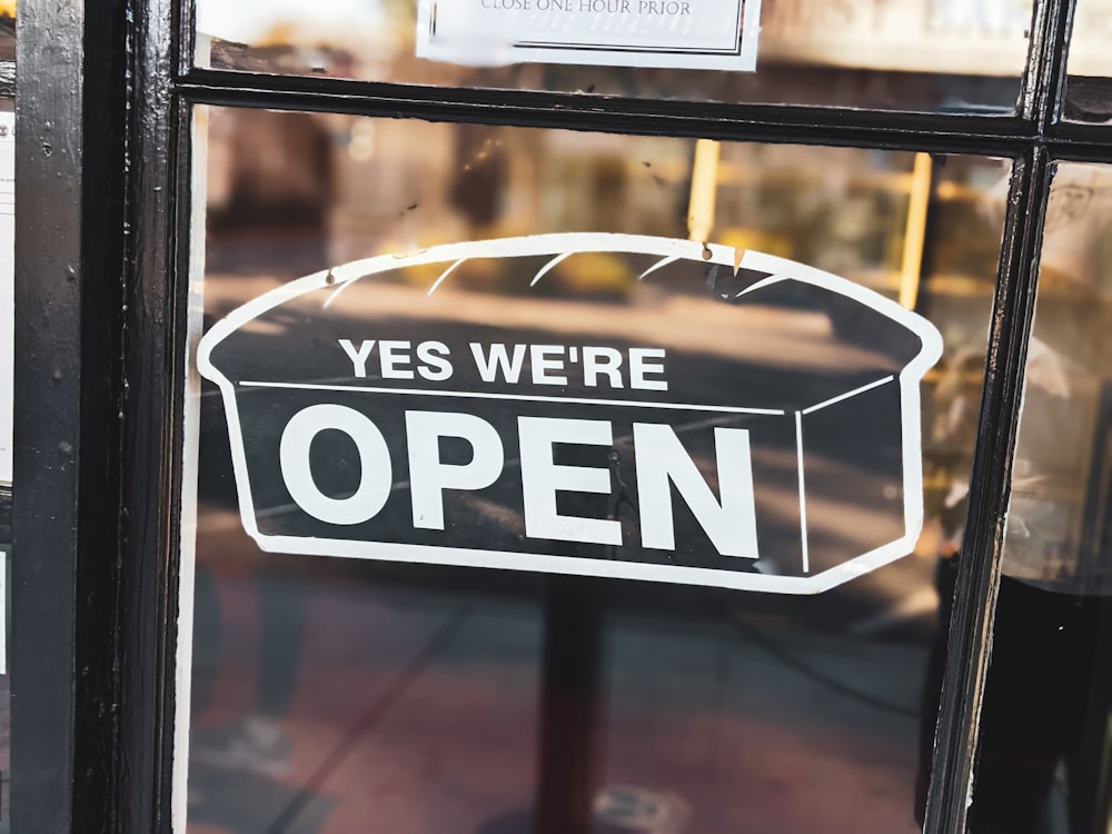 a sign that says yes we're open in a window