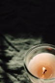 Close-up of a handcrafted scented candle glowing softly on a beige linen cloth