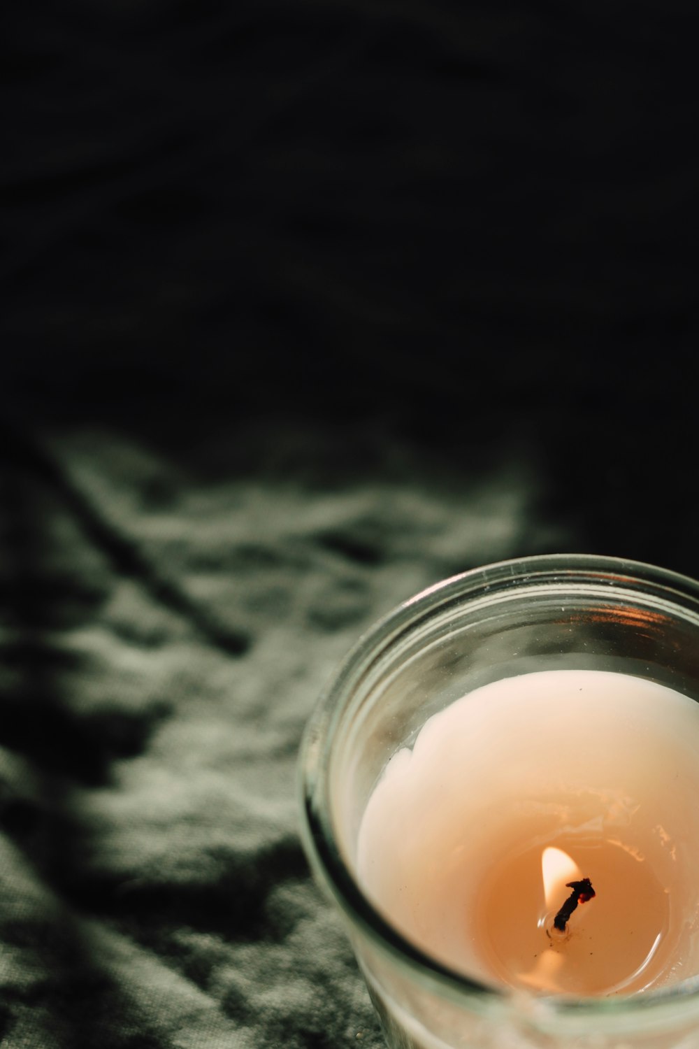 white candle in clear glass jar