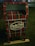 A decorative mailbox is adorned with a red and green plaid pattern and is labeled 'North Pole Airmail Express Service'. It is situated outdoors on a grass surface.
