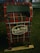 A decorative mailbox is adorned with a red and green plaid pattern and is labeled 'North Pole Airmail Express Service'. It is situated outdoors on a grass surface.