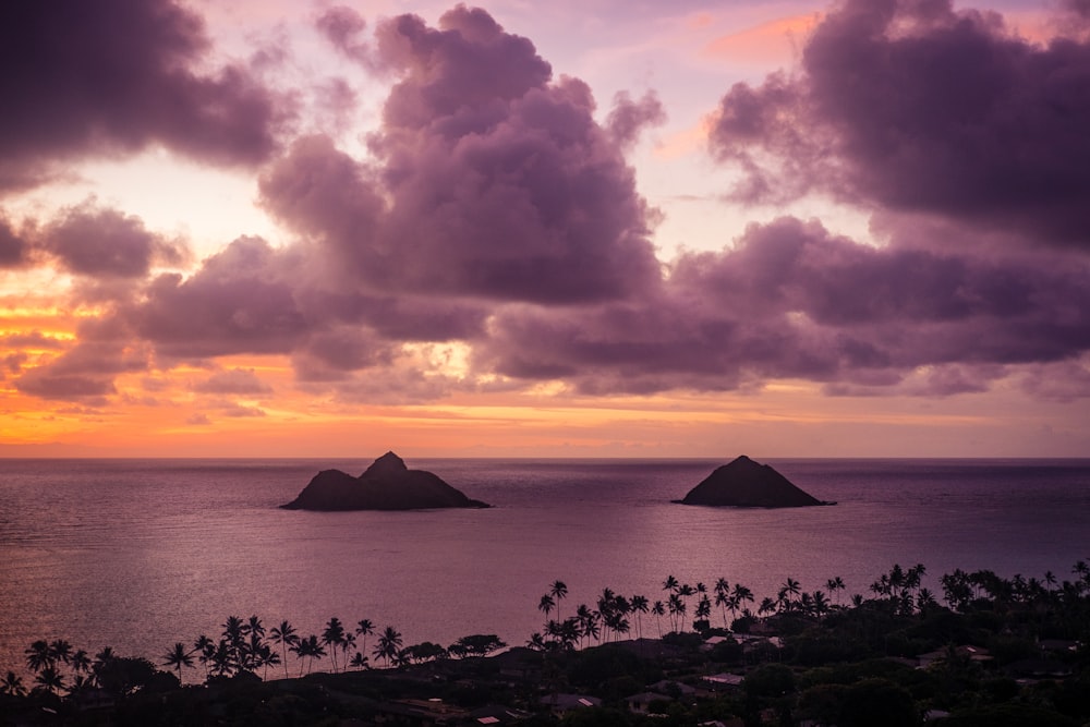 silhouette of mountain near body of water during sunset