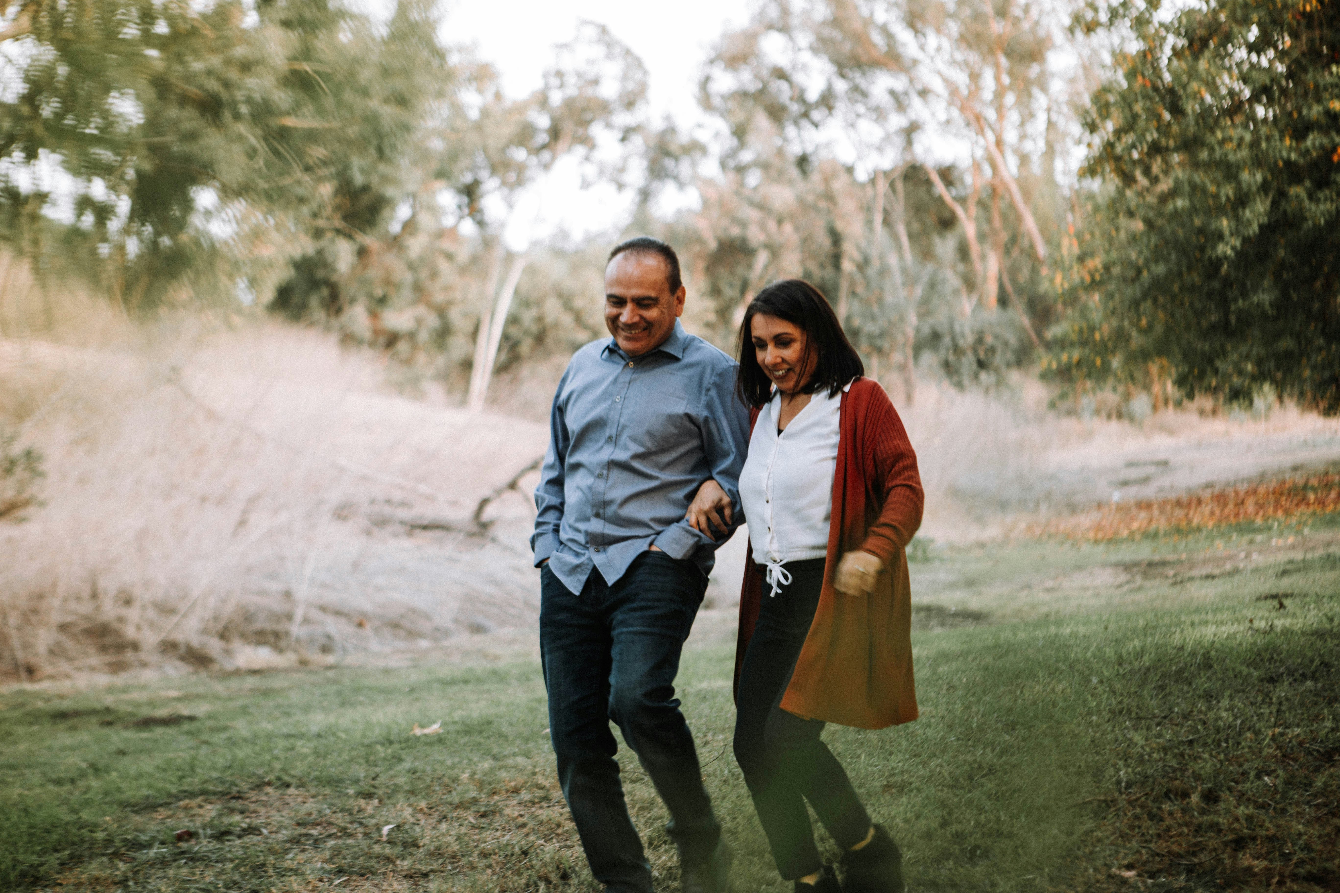 man in red dress shirt standing beside woman in gray long sleeve shirt