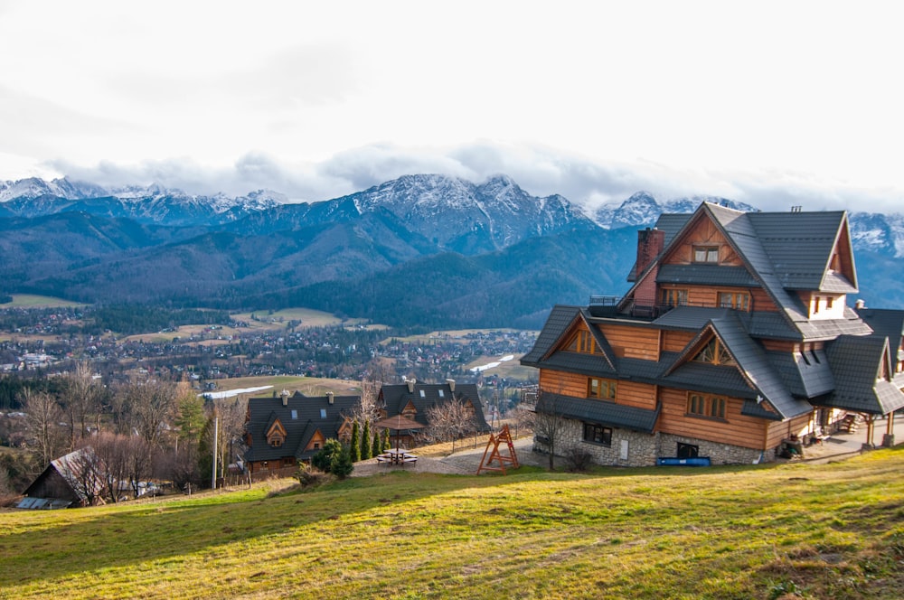 brown wooden houses on green grass field near mountain during daytime